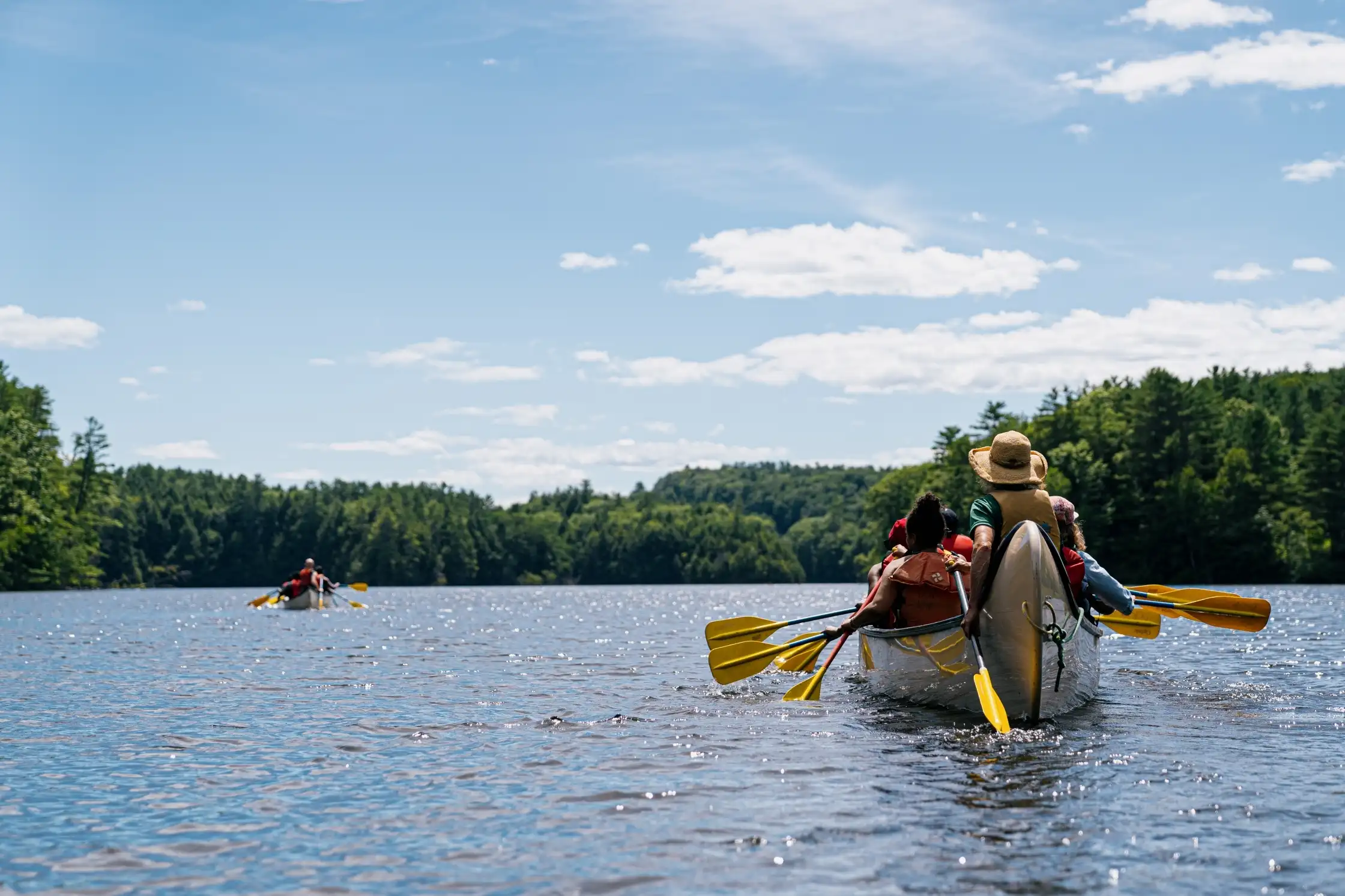 Two canoes full of people paddling down the Connecticut River